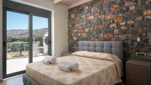 a bedroom with a stone wall and a bed with towels at Family Rhodes Villa 4 Bedrooms Villa Summer Memories Private Pool Lindos in vlicha +33 photos