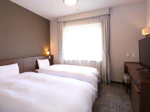 two beds in a hotel room with a window at Dormy Inn Premium Shibuya-jingumae in Tokyo
