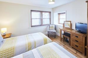 a bedroom with two beds and a desk with a television at Host & Stay - Sea Haven in Staithes +7 photos