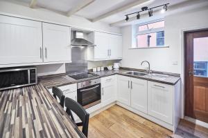 a kitchen with white cabinets and a table with chairs at Host & Stay - Sea Haven in Staithes