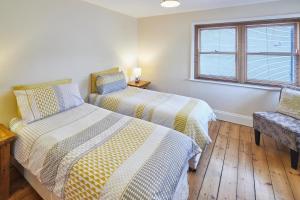 two beds in a room with a window and a chair at Host & Stay - Sea Haven in Staithes