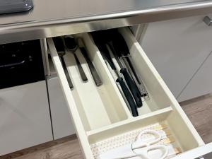 a drawer filled with knives and scissors underneath a counter at 江元浅草 in Tokyo