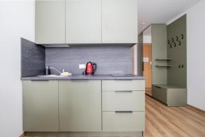 a kitchen with white cabinets and a red appliance at Studio W/Balcony @ManoŠventovė, By Cohost in Palanga