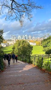 a group of people walking down a path in a park at Charming and Cosy Canary Wharf Room with Stunning Views in London +5 photos