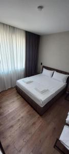 a bedroom with a bed with white sheets and wooden floors at Vila BABE in Vlorë