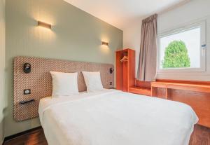 a bedroom with a large bed with a window at B&B HOTEL Mulhouse Kingersheim in Kingersheim