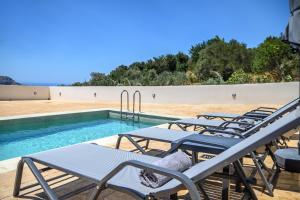 a row of lounge chairs next to a swimming pool at Villa Katerina 1 in Marioú
