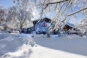 a blue house in the snow with snow covered trees at Studio im Loft in Oberstdorf
