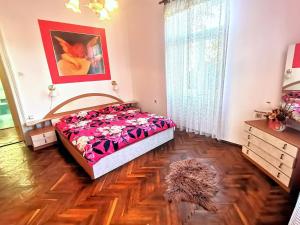 a bedroom with a bed in a room with wooden floors at Apartman Villa Adelina in Lovran