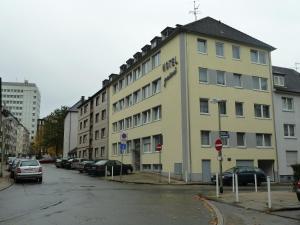 a building on a street with cars parked in a parking lot at Luise City - An der Philharmonie in Essen