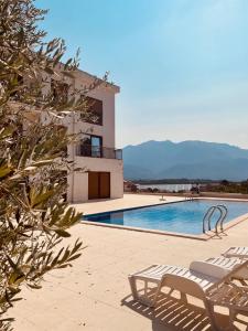 a swimming pool with two lounge chairs next to a building at Lavander Apartment W Pool and Private Beach in Tivat