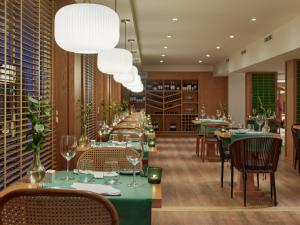 a restaurant with green tables and chairs and a large chandelier at H10 Gran Tinerfe - Adults Only in Adeje