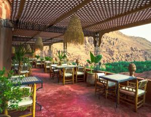 a restaurant with tables and chairs with a mountain in the background at Riad Rihana Dades in Boumalne