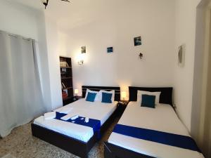 a bedroom with two beds with blue and white pillows at Cozy room in quiet neighbourhood in Athens
