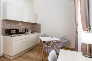 a kitchen with white cabinets and a table and chairs at Marbles Residence in Budapest
