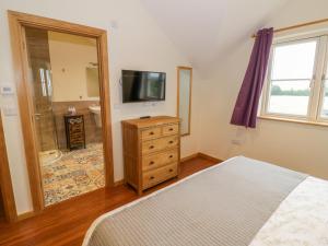 ein Schlafzimmer mit einem Bett und einem TV sowie ein Badezimmer in der Unterkunft Lavender Cottage in Warwick