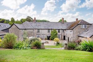 an old stone house with a garden in front of it at Sutton Barton Farmhouse in Honiton