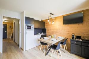 eine Küche mit einer Holzwand mit einem Tisch und Stühlen in der Unterkunft Le Berger - Apt dans résidence 4 étoiles au pied des pistes in Huez + 20 Fotos