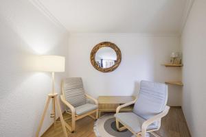 2 Stühle und ein Tisch in einem Zimmer mit Spiegel in der Unterkunft Le Berger - Apt dans résidence 4 étoiles au pied des pistes in Huez