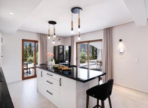 Villa Unique في نيدري: مطبخ بخزائن بيضاء وطاولة عمل سوداء