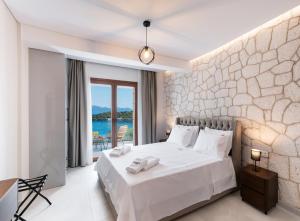 Villa Unique في نيدري: غرفة نوم بسرير ابيض وبجدار حجري +65 صورة