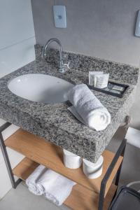 a bathroom counter with a sink and towels at Loft incrível em área nobre in Sinop