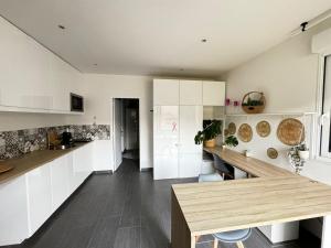 a kitchen with white cabinets and a wooden counter top at Studio indépendant et cosy in Basse-Goulaine