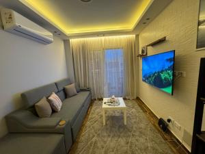 un salon avec un canapé et une télévision sur un mur dans l'établissement Madinaty - 2 BedroomBeauty, à Madinaty