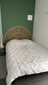 a bed in a bedroom with a wicker headboard at Studio indépendant et cosy in Basse-Goulaine