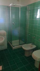 een groene betegelde badkamer met een toilet en een douche bij Villino Caddu in San Teodoro