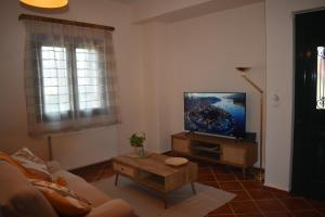a living room with a couch and a tv at Casa Katerina 1892 in Poros