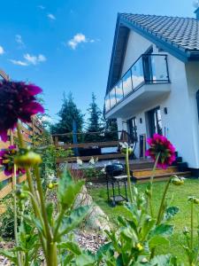 a house with a balcony and flowers in the yard at Apartament Masuria SPA Renata Rosłoń in Świętajno