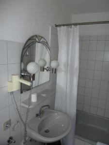 een witte badkamer met een wastafel en een spiegel bij Luise City - An der Philharmonie in Essen