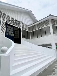 a white house with a blue door and stairs at The Vow Event Venue in Muar