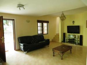 a living room with a black leather couch and a table at Hantana Forest Reserve Inn in Kandy