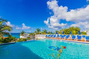 a large swimming pool with blue chairs and the ocean at La Vista Resort in Simpson Bay