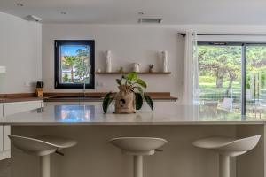 eine Küche mit einer großen weißen Theke mit Hockern in der Unterkunft Vue sur parc avec pétanque, basket, clim et Tramway in Castelnau-le-Lez