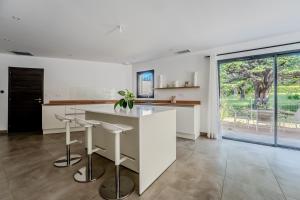 eine Küche mit einer weißen Insel und Hockern in der Unterkunft Vue sur parc avec pétanque, basket, clim et Tramway in Castelnau-le-Lez