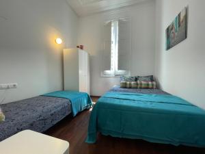 a room with two beds and a refrigerator in it at Centric Rooms Ghotic in Barcelona