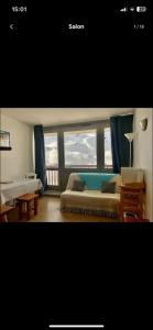 ein Schlafzimmer mit einem Bett und zwei großen Fenstern in der Unterkunft Studio cosy au bord des pistes à la mongie in Bagnères-de-Bigorre