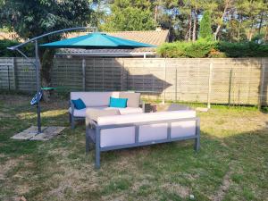 two chairs and a couch under an umbrella in a yard at Maison familiale in Le Teich