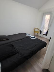 a black bed in a white room with a chair at Maison familiale in Le Teich