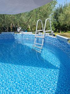 a blue swimming pool with a chair in it at APARTMAN LUCIA in Ražanac