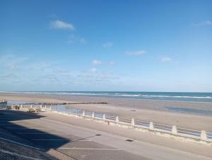 une plage avec une clôture blanche et l'océan dans l'établissement Lueurs des marées, à Merlimont