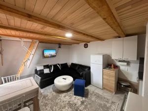 a living room with a black couch and a kitchen at Vikendica Kutnja njiva in Šavnik
