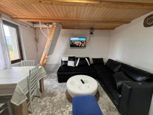a living room with a black couch and a table at Vikendica Kutnja njiva in Šavnik
