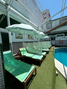 rząd krzeseł i parasoli obok basenu w obiekcie Hostal Avenida Andalucia - Solo Adultos w Sewilli