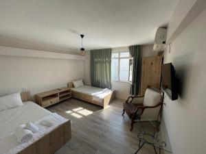 a bedroom with a bed and a chair and a television at Avio Pansiyon in Diyarbakır