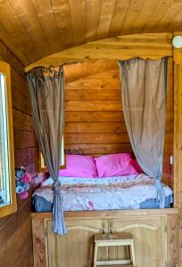 a bed in a log cabin with a canopy at Roulotte du Mas Rondole in Saillagouse