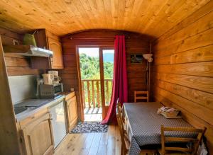 a kitchen with a table and a window in a cabin at Roulotte du Mas Rondole in Saillagouse
